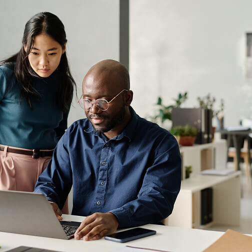 A man and woman collaborate on a laptop in an office, highlighting AI and decision support tools for healthcare.