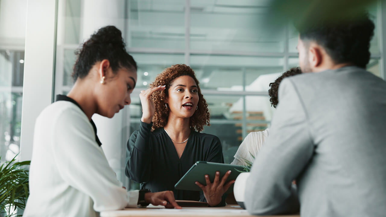 A diverse group of four people engaged in a discussion during a meeting in a modern office setting.