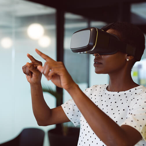 A woman wearing a virtual reality headset interacts with virtual objects, demonstrating immersive technology in a modern