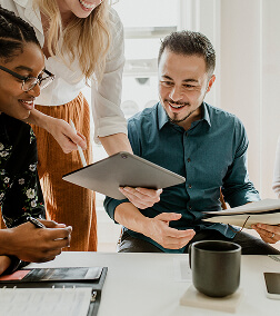 A group of diverse professionals reviewing documents and smiling during a meeting in an office setting.