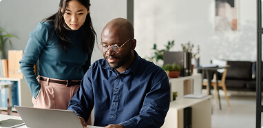 A man and woman collaborate on a laptop in a modern office, representing Diaconia-Home-Applied-R&D teamwork.