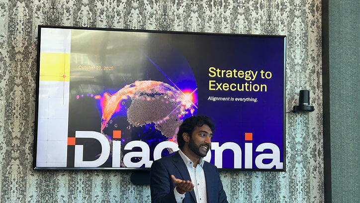 A man in a suit presents in front of a screen displaying "Strategy to Execution" and "Diaconia" with a digital globe and
