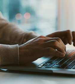 Hands typing on a laptop keyboard in a well-lit indoor setting.